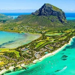 Veduta aerea di una penisola tropicale verde con una montagna imponente, circondata da acque oceaniche turchesi e spiagge di sabbia bianca.