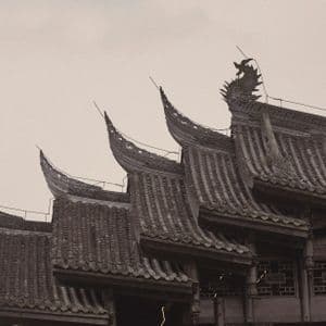 Eine Schwarz-Weiß-Fotografie zeigt die geschichteten, verzierten Ziegeldächer eines traditionellen ostasiatischen Gebäudes.
