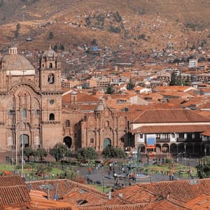 Una vista elevada de una histórica catedral de piedra en una concurrida plaza urbana, rodeada de edificios con tejados de teja roja en una ladera.
