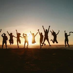 Un viaggio di gruppo WeRoad al tramonto, che salta in aria su una spiaggia.