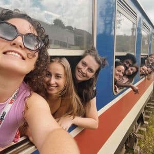 Un groupe WeRoad sourit pour un selfie en se penchant par les fenêtres d'un train en marche.