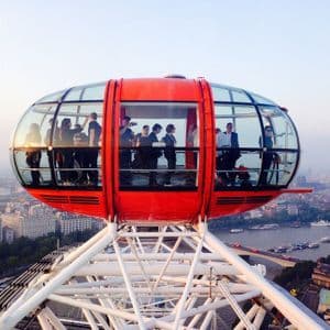 Un grupo de WeRoad en una cápsula roja de noria, con vistas a la ciudad y al río.
