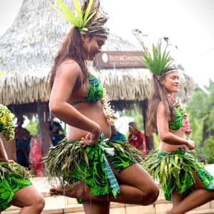 Un gruppo di donne in gonne di foglie verdi e copricapi elaborati esegue una danza tradizionale all'aperto sotto la pioggia.
