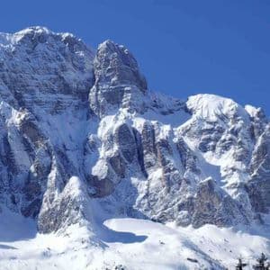 Le aspre cime rocciose delle montagne sono ricoperte da uno spesso strato di neve sotto un limpido cielo azzurro.