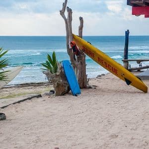 Una tavola da surf gialla per il salvataggio e altre tavole da surf sono appoggiate su una spiaggia sabbiosa con l'oceano sullo sfondo.