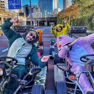 Un viaggio di gruppo WeRoad con persone in costume che posano mentre guidano go-kart su una strada cittadina.