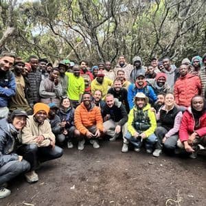 Un grande gruppo WeRoad in posa per una foto in una radura nel bosco, con abbigliamento da trekking.