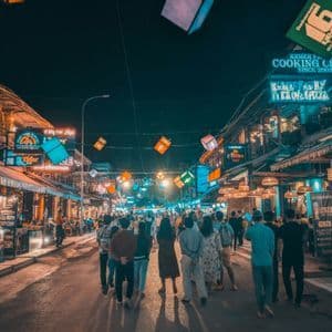 Un viaggio di gruppo WeRoad percorre una strada affollata di notte, illuminata da insegne al neon colorate e lanterne appese.