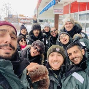 Un gruppo WeRoad in viaggio si fa un selfie, indossando caldi abiti invernali in un paesaggio innevato.