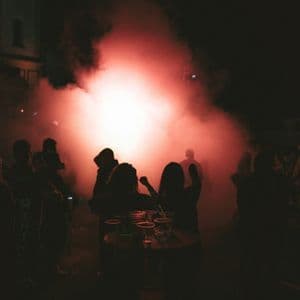 Un voyage de groupe WeRoad se détachant sur une lumière rouge vif et de la fumée lors d'une fête nocturne en plein air.