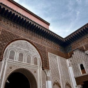 Vista en contrapicado de un patio de edificio ornamentado, con intrincadas tallas de madera y yeso en las paredes y arcos, bajo un cielo nublado.