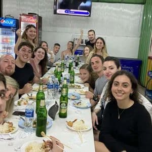 Un grand groupe WeRoad sourit pour une photo, attablé à une longue table dans un restaurant décontracté.