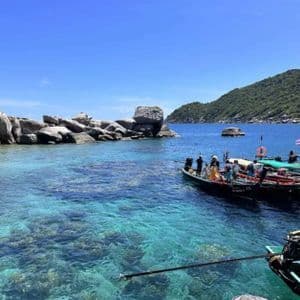 Un voyage de groupe WeRoad en bateaux à longue queue dans une baie tropicale aux eaux turquoise claires et aux grands rochers.