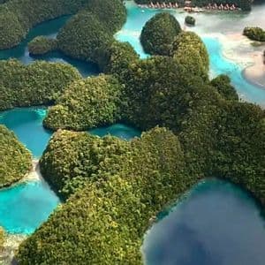 Una vista aerea di numerose piccole isole verdi sparse in acque calme, turchesi e blu profondo.