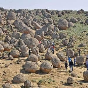 Un viaggio di gruppo WeRoad attraversa un paesaggio unico, ricco di grandi massi rotondi sparsi su una collina erbosa.