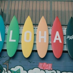 Six colorful surfboards mounted in a row on a wall, spelling out the word ALOHA.