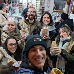 Un grupo de WeRoad sonríe para una selfie en una panadería, cada uno con un pastel de chimenea tradicional.