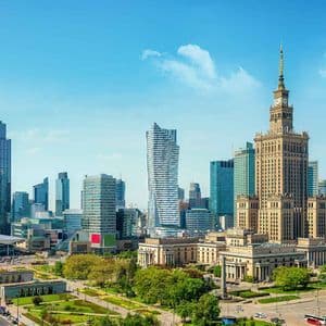 Une ligne d'horizon urbaine avec des gratte-ciel modernes en verre et un bâtiment historique emblématique avec une tour d'horloge sous un ciel bleu clair.