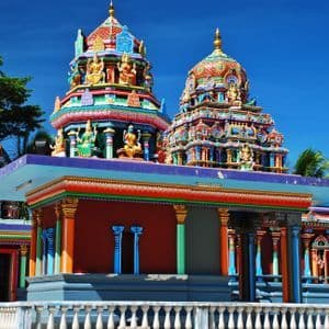 Un tempio indù dai colori vivaci con torri finemente intagliate e ornate da statue, sullo sfondo di un cielo azzurro e limpido.