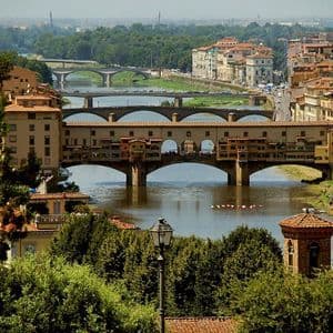 Veduta diurna sopraelevata di un ponte storico con edifici, che attraversa un ampio fiume in una città europea.