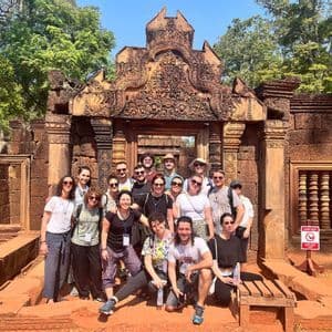 Un viaggio di gruppo WeRoad in posa per una foto davanti a un antico ingresso di tempio in pietra, riccamente scolpito.