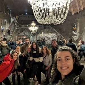 Un viaje en grupo de WeRoad se toma una selfie dentro de una gran caverna subterránea decorada con ornamentadas lámparas de araña de cristal.
