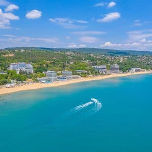 Vista aerea di due moto d'acqua su acque turchesi, vicino a una spiaggia sabbiosa con hotel e colline verdi.