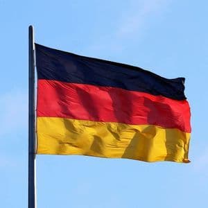 La bandiera tedesca con le sue strisce nere, rosse e oro che sventola su un'asta contro un cielo azzurro chiaro.