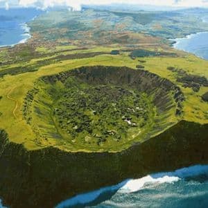 Una vista aerea di un'isola verdeggiante con un grande cratere vulcanico in primo piano, circondata dall'oceano.