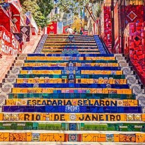 Eine Untersicht auf die farbenfrohe Kacheltreppe Escadaria Selarón in Rio de Janeiro, mit Menschen an der Spitze.