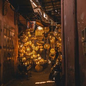 De nombreuses lanternes métalliques illuminées et ouvragées suspendues dans une ruelle de marché étroite et faiblement éclairée.