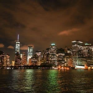 Lo skyline illuminato di una città con molti grattacieli di notte, visto dall'acqua.