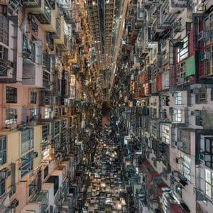 Veduta dal basso, guardando in alto attraverso lo stretto varco tra imponenti condomini densamente ravvicinati, di notte.