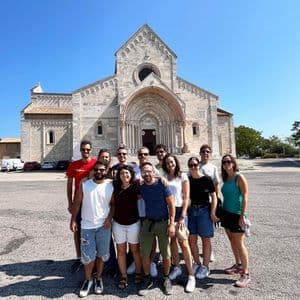 Un gruppo WeRoad posa per una foto in una piazza assolata davanti a una grande cattedrale in pietra.