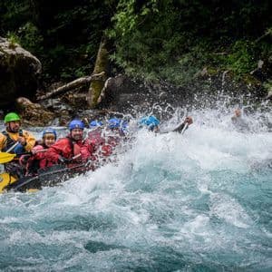 Un viaggio di gruppo WeRoad, indossando caschi e giubbotti di salvataggio, fa rafting in acque bianche turbolente, pagaiando tra grandi spruzzi.