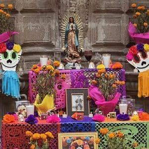 Un altare colorato del Giorno dei Morti decorato con calendule, papel picado, teschi, ritratti e una statua della Vergine Maria.