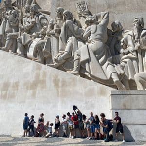 Un groupe WeRoad en voyage posant pour une photo au pied d'un grand monument en pierre avec des figures sculptées.
