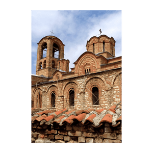 Una vecchia chiesa costruita in pietra e mattoni, con un campanile e cupole sotto un cielo azzurro nuvoloso.