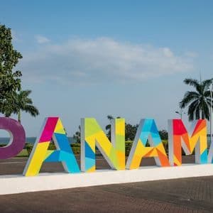 Das Wort 'PANAMA' in großen, bunten, dreidimensionalen Buchstaben auf einer Promenade am Meer mit Palmen.