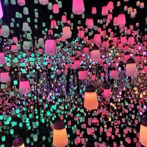 An art installation of numerous colorful hanging lanterns reflected infinitely in a dark, mirrored room.