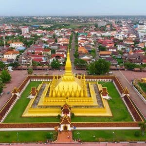 Una vista aerea di un grande tempio dorato con uno stupa centrale, racchiuso da mura e circondato da una città estesa.