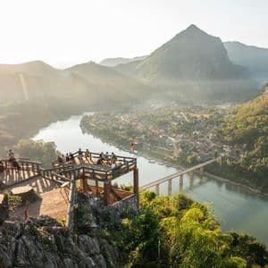 Un viaggio di gruppo WeRoad su un belvedere di legno, ammirando l'alba su una valle fluviale e le montagne.
