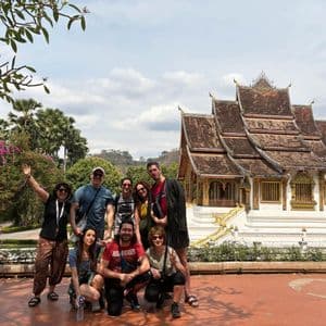 Un gruppo WeRoad posa per una foto in un cortile di fronte a un tradizionale tempio dai tetti multipli.