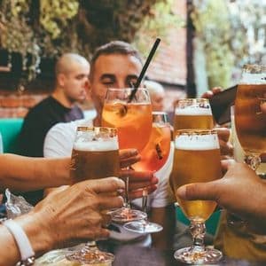 Eine WeRoad-Gruppe stößt draußen an einem Tisch mit Bier und Cocktails an.
