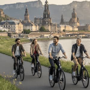 Eine WeRoad Gruppenreise: Radfahrer auf einem Pfad entlang eines Flusses mit historischer Stadt im Hintergrund.