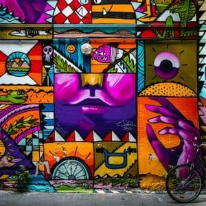 Ein schwarzes Fahrrad steht auf einem Bürgersteig vor einer farbenfrohen Graffiti-Wand.