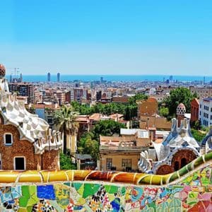 Stadtansicht mit Blick zum Meer, zwei einzigartige Gebäude im Vordergrund, gesehen über eine bunte Mosaikmauer.