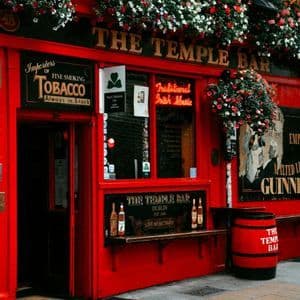 Die leuchtend rote Fassade des The Temple Bar Pub in Dublin, geschmückt mit bunten Blumenkästen über dem Eingang.