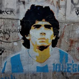 Un graffito a stencil di Diego Maradona su un muro imbrattato, che lo raffigura con la maglia della nazionale argentina.