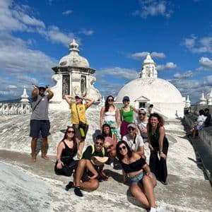 Un voyage de groupe WeRoad pose pour une photo sur un toit blanc avec des dômes sous un ciel bleu.